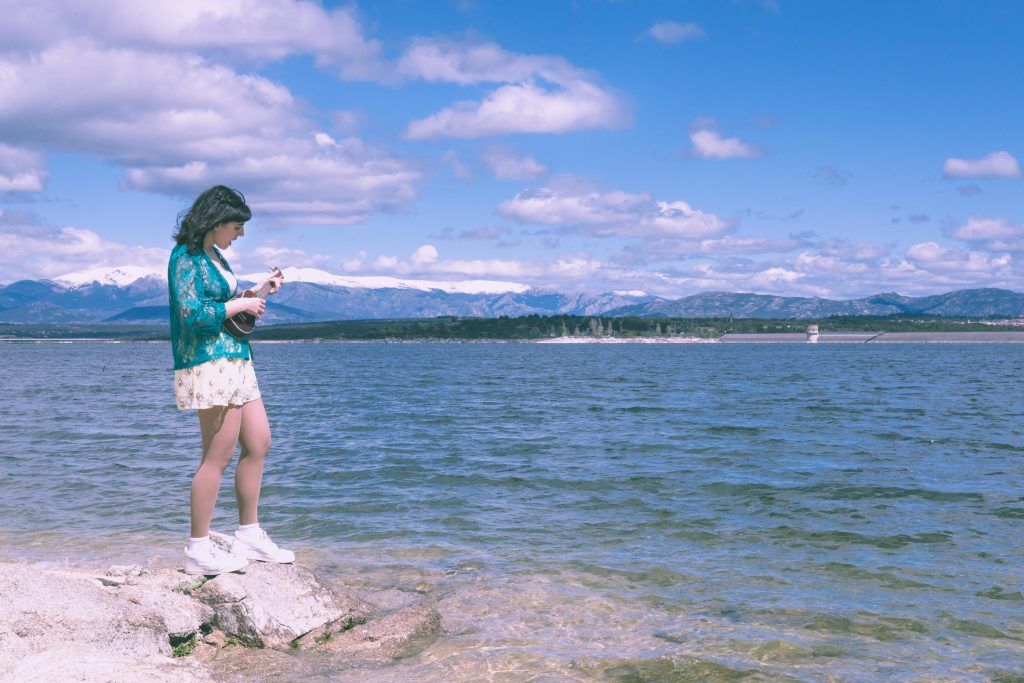 Laura Antona, conocida como Margo Madison, toca el ukelele con el agua y la sierra madrileña de fondo en el videoclip de Like a mermaid